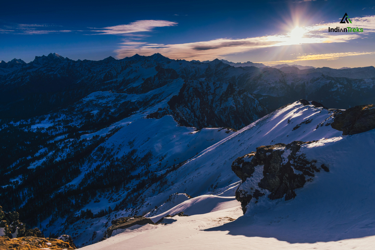 Sunrise over Kedarkantha peak with trekkers enjoying the view in Uttarakhand Himalayas.