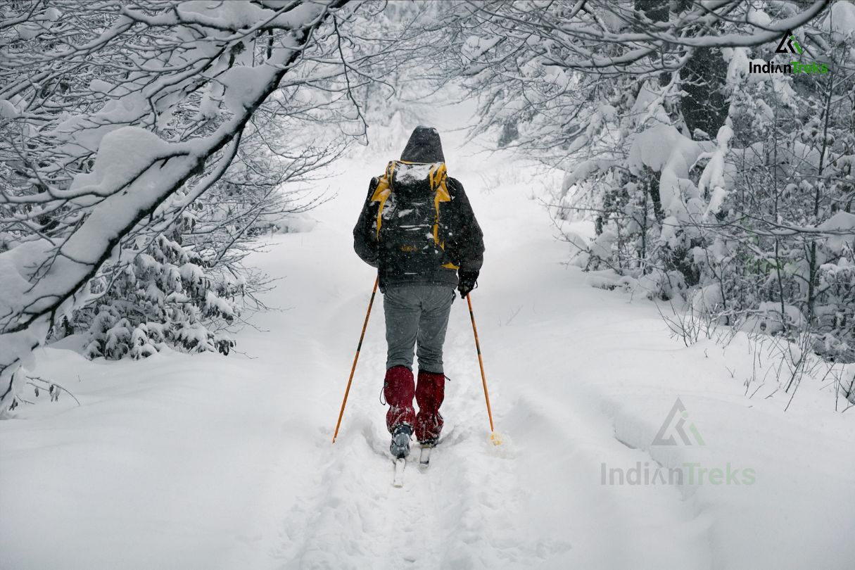 Trekker descending safely using poles on a snowy slope